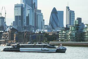 tourboat på flod Thames, horisont av ekonomiskt distrikt i bakgrund foto