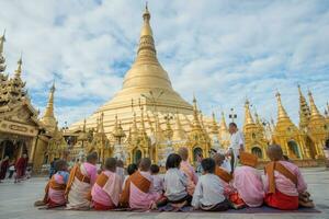 yangon, myanmar -17 december 2016 - grupp av burmesiska nunnor Sammanträde och bön- i främre av shwedagon pagod de mest helig plats i yangon, myanmar. foto