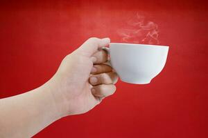 hand innehav vit kaffe kopp med röd bakgrund foto