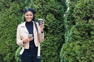 glad afroamerikansk kvinna på gatan med kaffe foto
