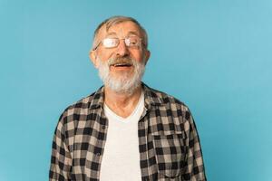 porträtt pensionerad gammal man med vit hår och skägg skratt upphetsad över blå Färg bakgrund foto