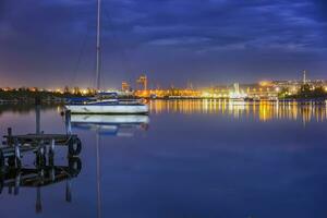 Fantastisk se från en pir till Yacht och stad lampor vatten reflexion foto