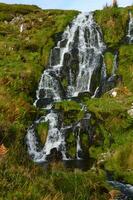 grön mossa växande på de stenar av en vattenfall foto