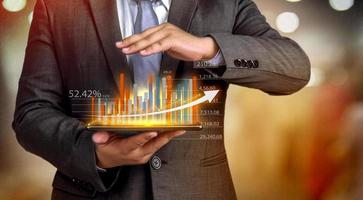 affärsmän håller en surfplatta, planerar och strategi och visar virtuella hologram med statistik, finansiella diagram, värdepapper och diagram på en mörk bakgrund. begreppet affärstillväxt foto