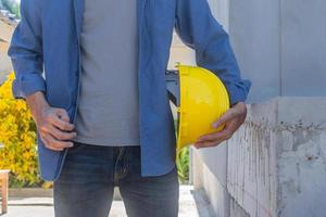 arbetarkitekt som rymmer den gula hjälmen i byggnadskonstruktion foto