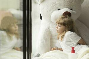 en ung flicka Sammanträde i säng med en stor teddy Björn foto