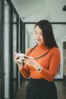 asiatisk kvinna turist i eleganta ha på sig tar foton använder sig av årgång kamera, kreativ professionell kvinna fotograf framställning urban Foto session under solig dag