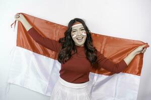 Lycklig leende indonesiska kvinna innehav Indonesiens flagga till fira indonesien oberoende dag isolerat över vit bakgrund. foto