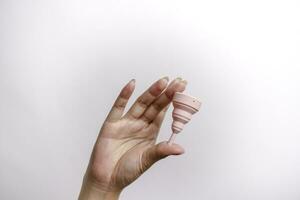stänga upp av kvinna hand innehav menstruations- kopp över vit bakgrund. kvinnor hälsa begrepp, noll avfall alternativ foto