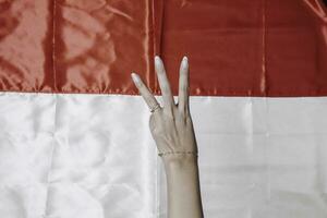 händer gestikulerar tecken av siffra isolerat förbi indonesiska röd och vit flagga. Indonesiens oberoende dag begrepp foto