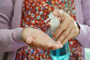 asiatisk senior kvinna trycker blå alkoholdesinfektionsgel för handtvätt skydda infektion coronavirus. foto
