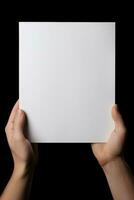 en mänsklig hand innehav en tom ark av vit papper eller kort isolerat på svart bakgrund. ai genererad foto