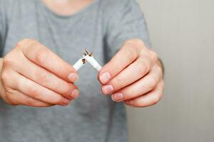 ung kvinna innehav bruten cigarett i henne händer stänga foto