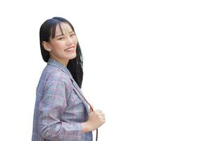 självsäker ung asiatisk kvinna vem bär brun randig blazer och axel väska ler lyckligt och utseende på de kamera som hon pendla medan arbetssätt isolerat på vit bakgrund. foto