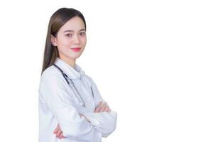 ung professionell asiatisk kvinna läkare stående med vapen korsade. bär vit morgonrock och stetoskop på undersökning rum i de sjukhus medan arbetssätt isolerat på vit bakgrund.. foto