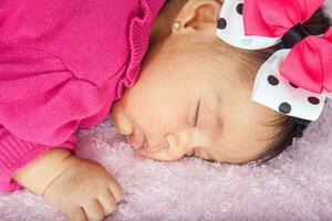 närbild av en ljuv liten ett månad bebis sovande klädd i rosa bär en rosett foto