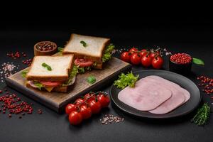 utsökt smörgås med rostat bröd, skinka, tomater, ost och sallad foto