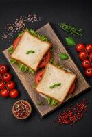 utsökt smörgås med rostat bröd, skinka, tomater, ost och sallad foto