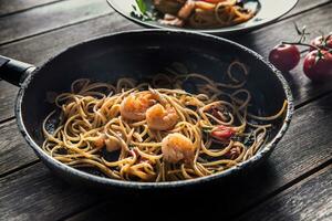 pasta spaghetti på tallrik och panorera med räka tomat sås toater och örter. italiensk eller medelhavs kök foto