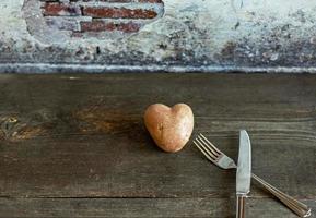 röd potatis i form av ett hjärta på en träbakgrund med en gaffel och kniv foto