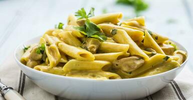 pasta pene med kyckling bitar svamp parmesan ost sås och ört dekoration. pene lura pollo - italiensk eller medierranean kök foto