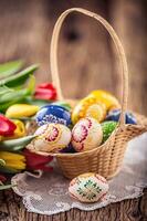 påsk. hand tillverkad målad påsk ägg i korg och vår tulpaner. foto