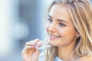 invisalign ortodonti begrepp - ung attraktiv kvinna innehav - använder sig av osynlig tandställning eller tränare foto