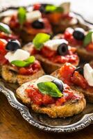 bruschetta rostat bröd med mozzarella tomater oliver och basilika. foto