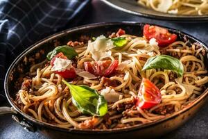 italiensk pasta spaghetti bolognese i gammal panorera med tomater parmesan ost och basilika foto