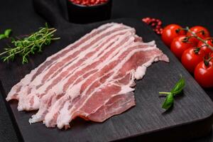 färsk rå bacon skära in i skivor med salt, kryddor och örter foto
