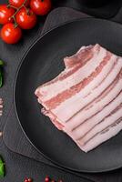 färsk rå bacon skära in i skivor med salt, kryddor och örter foto