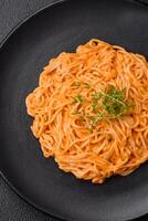 utsökt färsk pasta bestående av tunn spaghetti, röd pesto rosso sås med kryddor och örter foto