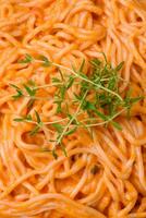 utsökt färsk pasta bestående av tunn spaghetti, röd pesto rosso sås med kryddor och örter foto
