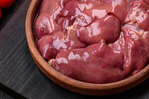 färsk rå kyckling eller Kalkon lever i en keramisk tallrik med salt, kryddor och örter foto