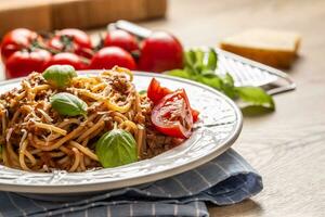 italiensk pasta spaghetti bolognese eras på vit tallrik med parmesan ost och basilika foto