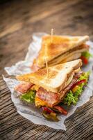 klubb smörgås på en rustik tabell häxa kyckling, bacon, peppar och sallad. foto