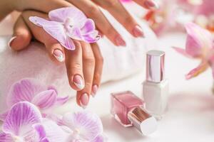 skön nagel manikyr med dekoration från rosa orkide foto