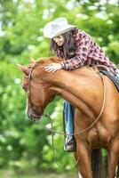 flicka klappa en häst den där utseende tillbaka under en sommar natur rida foto