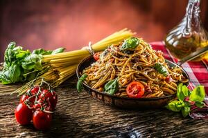 italiensk pasta spaghetti med tomat sås oliv olja basilika och parmesan ost i gammal panorera foto