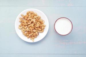 cashewnötter på plattan och glas på mjölk på bordet foto