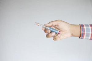 hand som håller insulinpennor på vit bakgrund, närbild foto