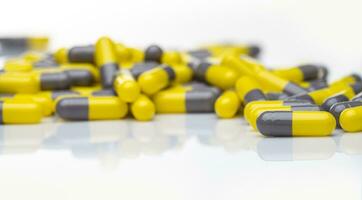 närbild gul och grå kapsel piller på vit bakgrund. recept läkemedel. farmaceutisk industri. hälsa och medicinsk vård begrepp. apotek Produkter. kapsel piller produktion tillverkning. foto