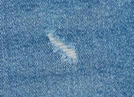 fragment av blå jeans tyg med en hål, full ram, stänga upp foto