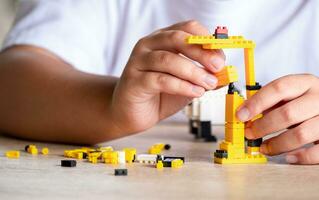 stänga upp asiatisk flicka 5-6 år gammal unge spelar med LEGO tegelstenar eller leksak på Hem, asiatisk flickor koppla av med spelar tegel block på trä- tabell och njut av spelar leksaker. foto