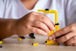 stänga upp asiatisk flicka 5-6 år gammal unge spelar med LEGO tegelstenar eller leksak på Hem, asiatisk flickor koppla av med spelar tegel block på trä- tabell och njut av spelar leksaker. foto