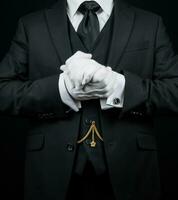 porträtt av butler i mörk kostym och vit handskar ivrig till vara av service. foto