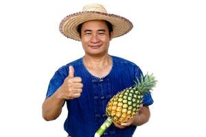 asiatisk man jordbrukare bär hatt, blå skjorta, innehar ananas frukt, isolerat på vit bakgrund. begrepp, jordbrukare är Lycklig och stolt från håller på med organisk lantbruk. thai jordbrukare. foto