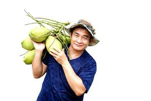 asiatisk man bära organisk kokos frukt på axel, isolerat på vit bakgrund. begrepp , lantbruk beskära i thailand.thai jordbrukare växa kokosnötter till sälja. sommar frukter. foto