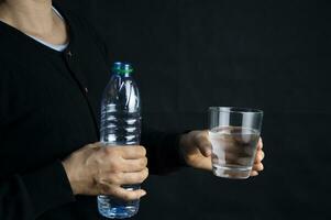 kvinna innehav en glas av vatten de begrepp av dricka tillräckligt vatten varje dag för Bra hälsa. foto