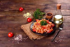 läcker färsk pasta med tomatsås med kryddor och örter på en mörk bakgrund foto